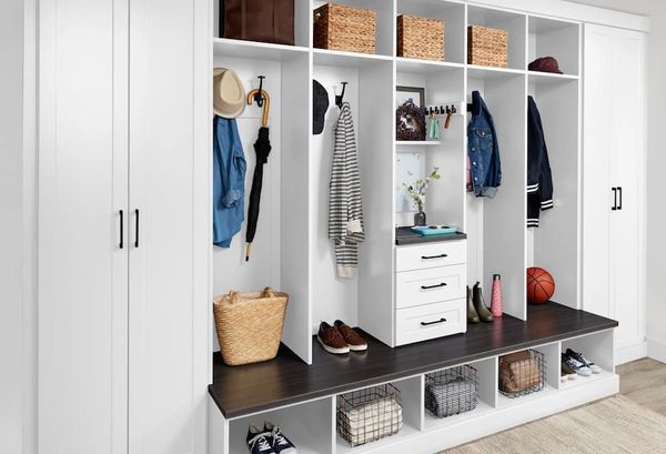 White mudroom storage with hooks, baskets, and seating bench.