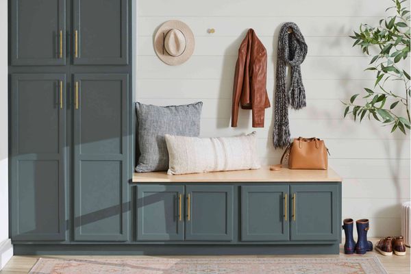 Cozy entryway with bench, cushions, and hanging coat, scarf, and hat.