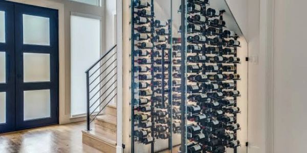 Modern wine rack under staircase with glass doors.