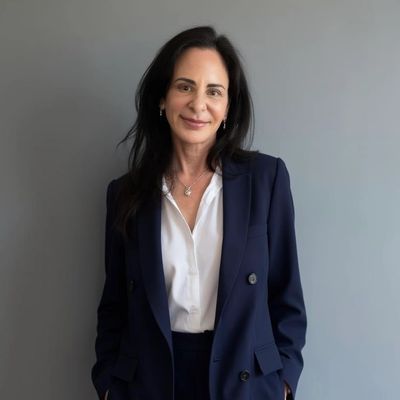 Professional woman in a navy suit smiling against a gray background.