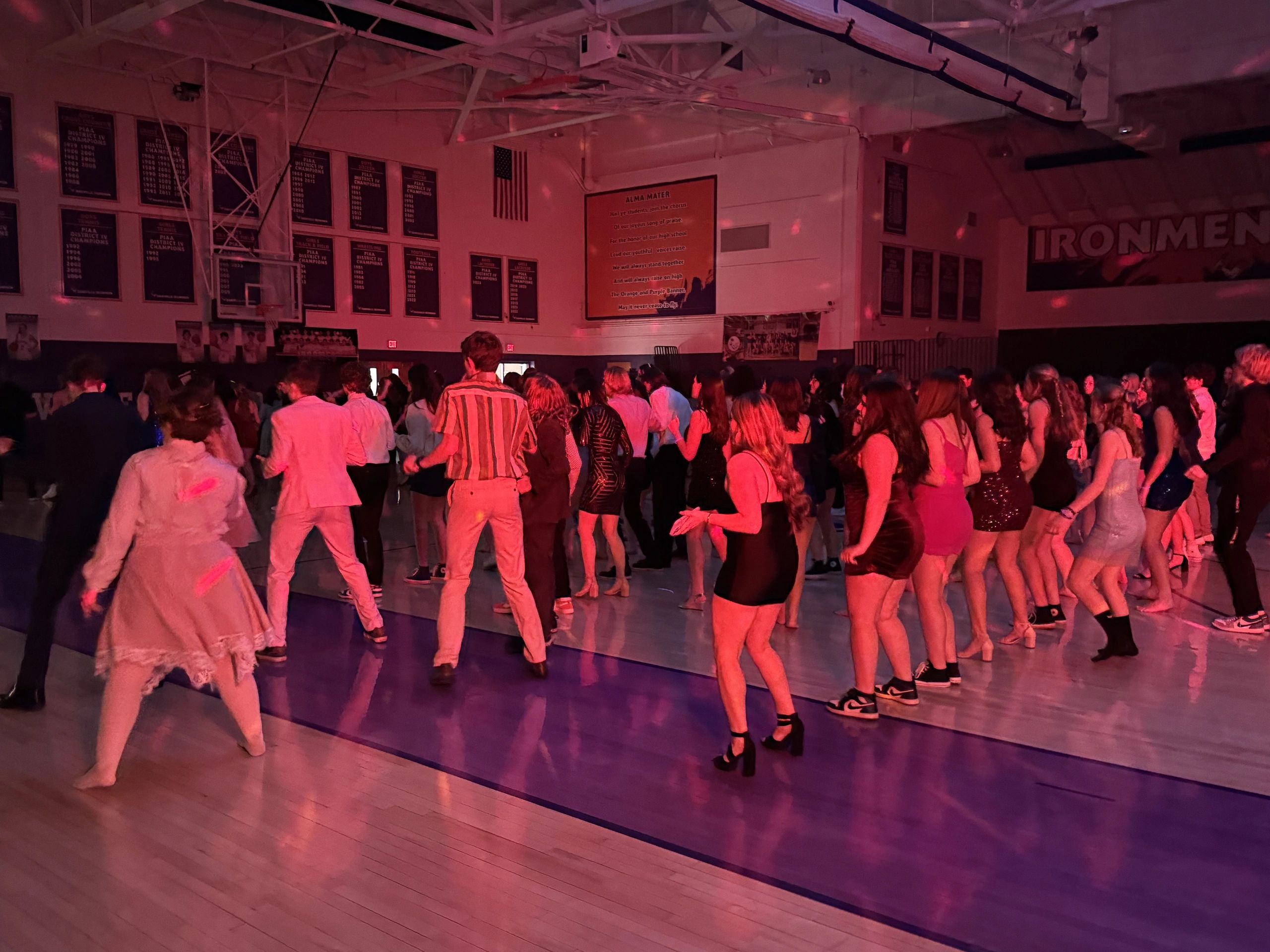 High school dance with students enjoying in a dimly lit gymnasium.