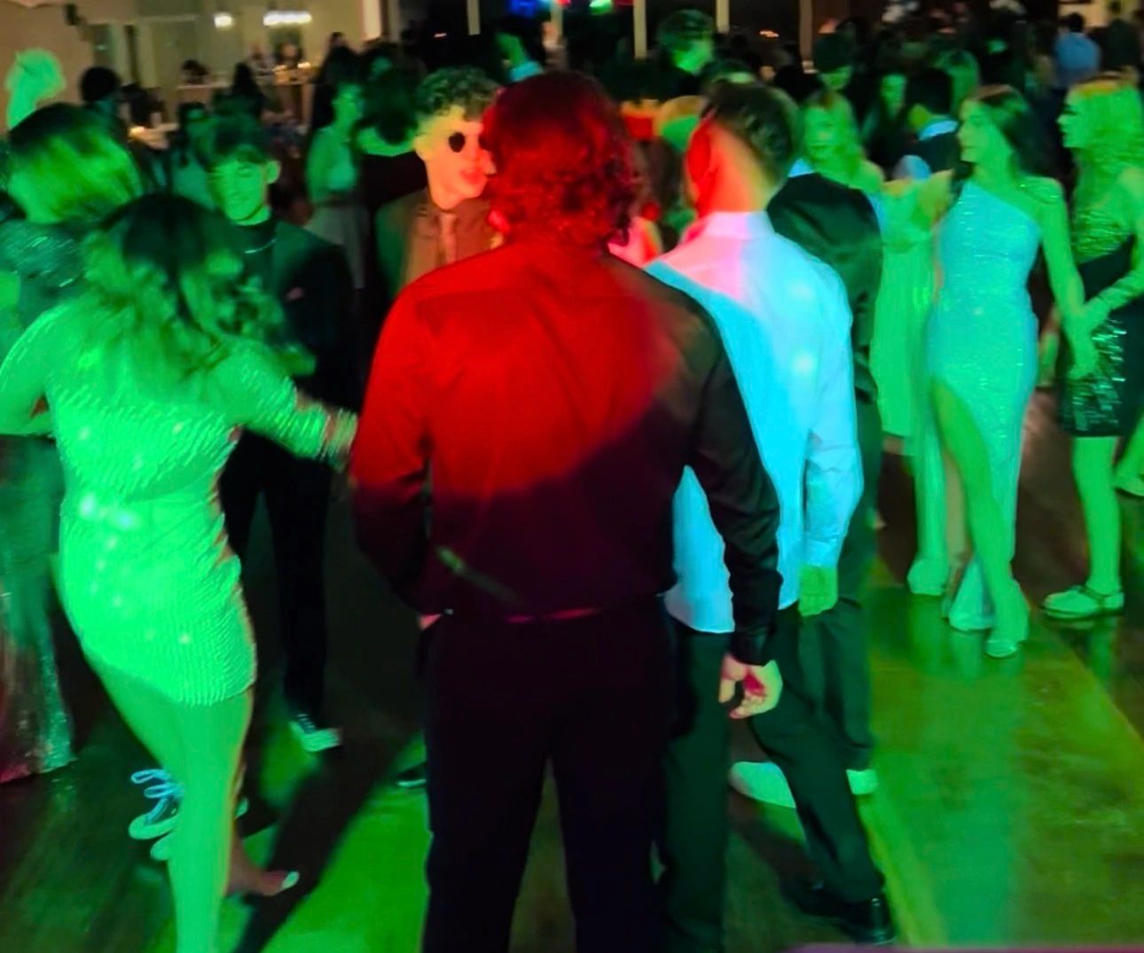 A lively party with people dancing under colorful lights.