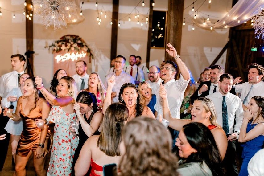 A lively group of people dancing and celebrating indoors with festive lighting.