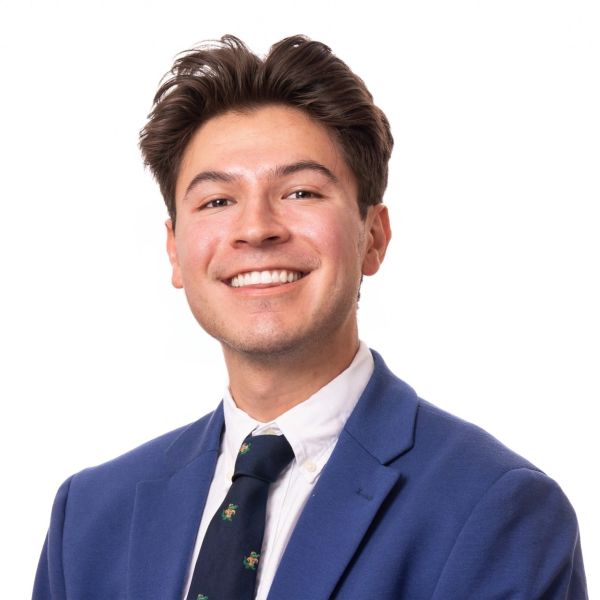 Young man smiling in a blue blazer and tie.