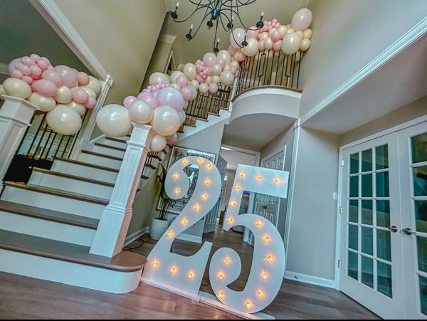 Decorated staircase with balloons and illuminated number 25 for celebration.