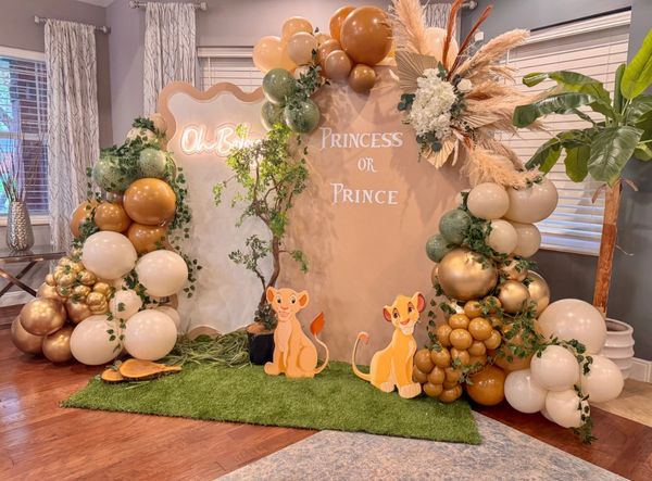 Lion King themed gender reveal party setup with balloons and greenery.