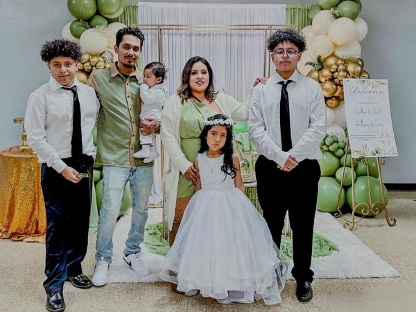 Family portrait at a celebration with green and gold balloon decor.