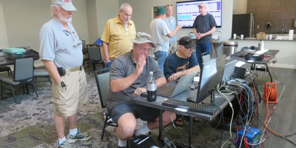 Group of men working with computers and cables in a meeting room.