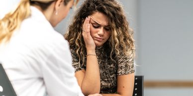 A distressed woman talks to a healthcare professional.