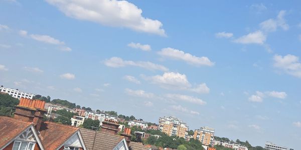 Blue sky with clouds over city rooftops.