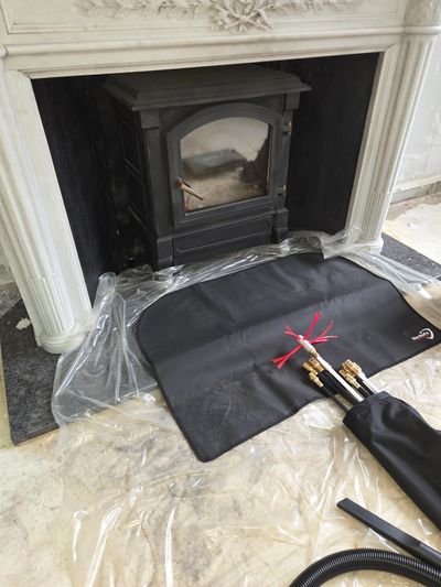 Black wood stove inside a white marble fireplace.