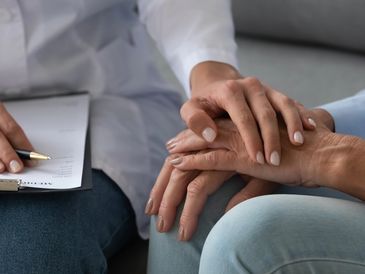 A psychologist holding the hands of a patient