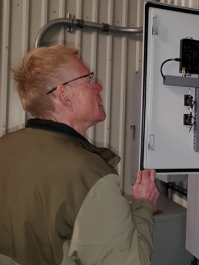 Man inspecting an open electrical control panel inside an industrial setting.
