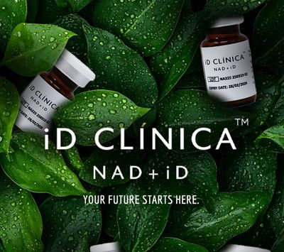 iD Clinica NAD+iD supplement bottles on fresh green leaves with water droplets.