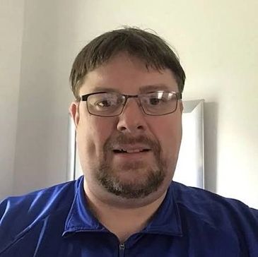 Man wearing glasses and blue shirt smiling.