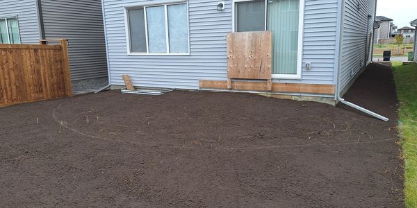 Backyard with freshly tilled soil next to a house.