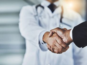 Doctor and businessman shaking hands in agreement.