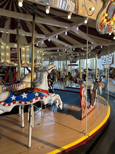 A vintage carousel horse with patriotic decorations inside a classic merry-go-round.