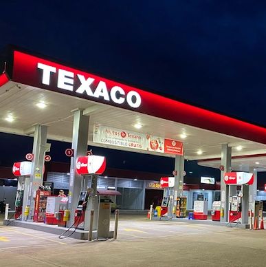 Texaco gas station illuminated at night with multiple fuel pumps.