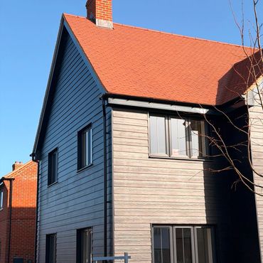 Modern house with mixed siding and red roof.
