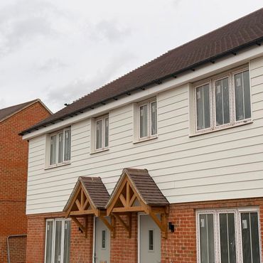 Front view of modern two-story houses with white cladding and brick lower walls.