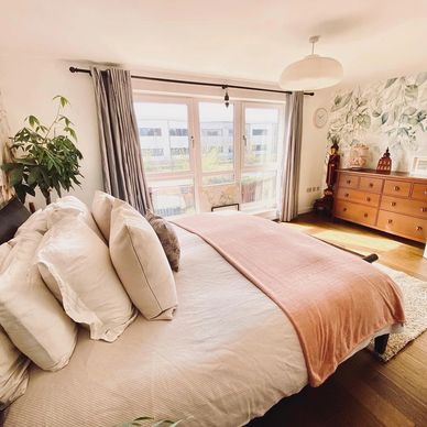 Bright bedroom with a large bed and wooden dresser.