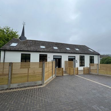 White building with a wooden fence under cloudy sky.