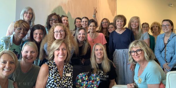 Group of smiling women posing indoors for a friendly photo.