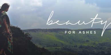 Person overlooking lush green hills under a cloudy sky with the text 'beauty for ashes'.