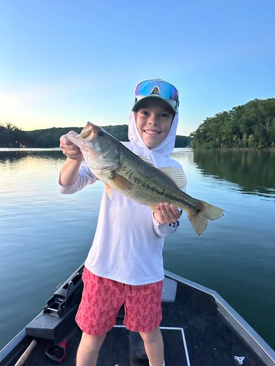Boy holding a large fish on a boat.