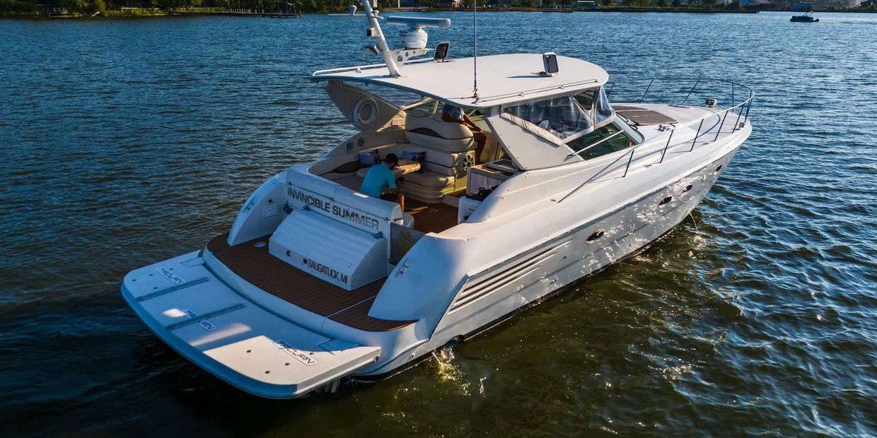 White luxury yacht named Invincible Summer on calm water.