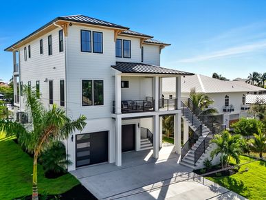 A modern three-story house with a garage and outdoor staircase.