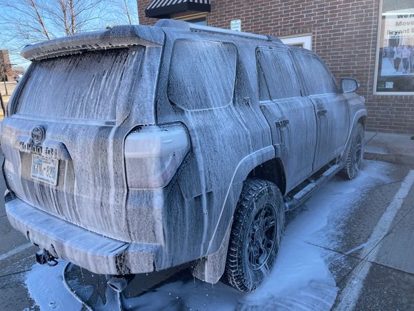 SUV covered in soap foam during a car wash.