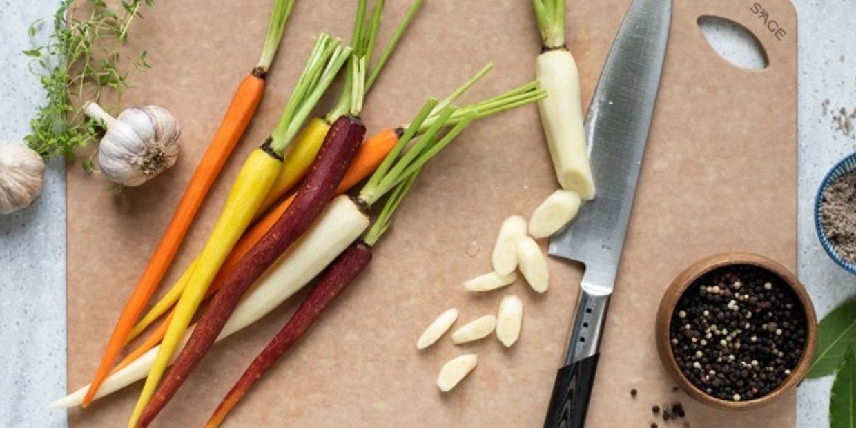 Colorful carrots and garlic on a cutting board with spices and herbs.