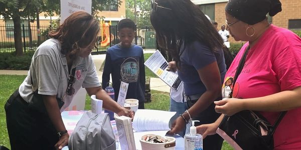 People interacting at an information booth outdoors.