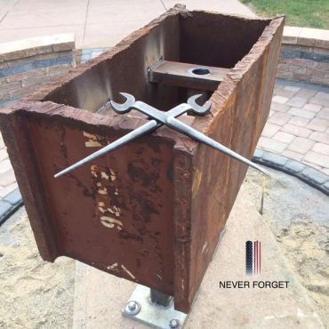 Memorial with a rusted steel beam and wrenches.