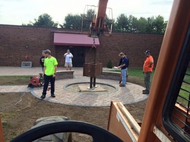 Workers installing a circular metal structure with machinery.