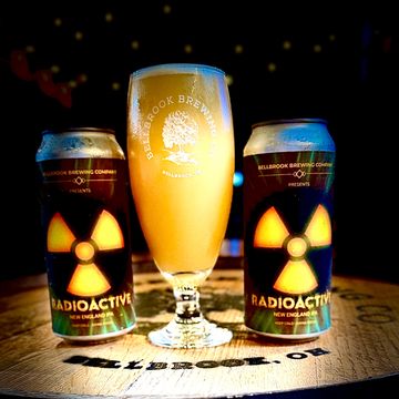 Two cans of Radioactive New England IPA with a filled Bellbrook Brewing glass.