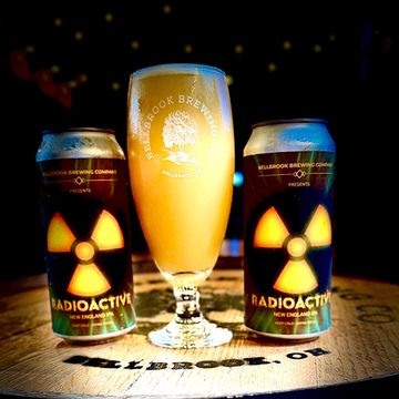 Two cans of Radioactive New England IPA with a filled Bellbrook Brewing glass.