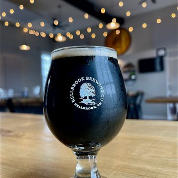 A glass of dark beer from Bellbrook Brewing Co. on a wooden table.