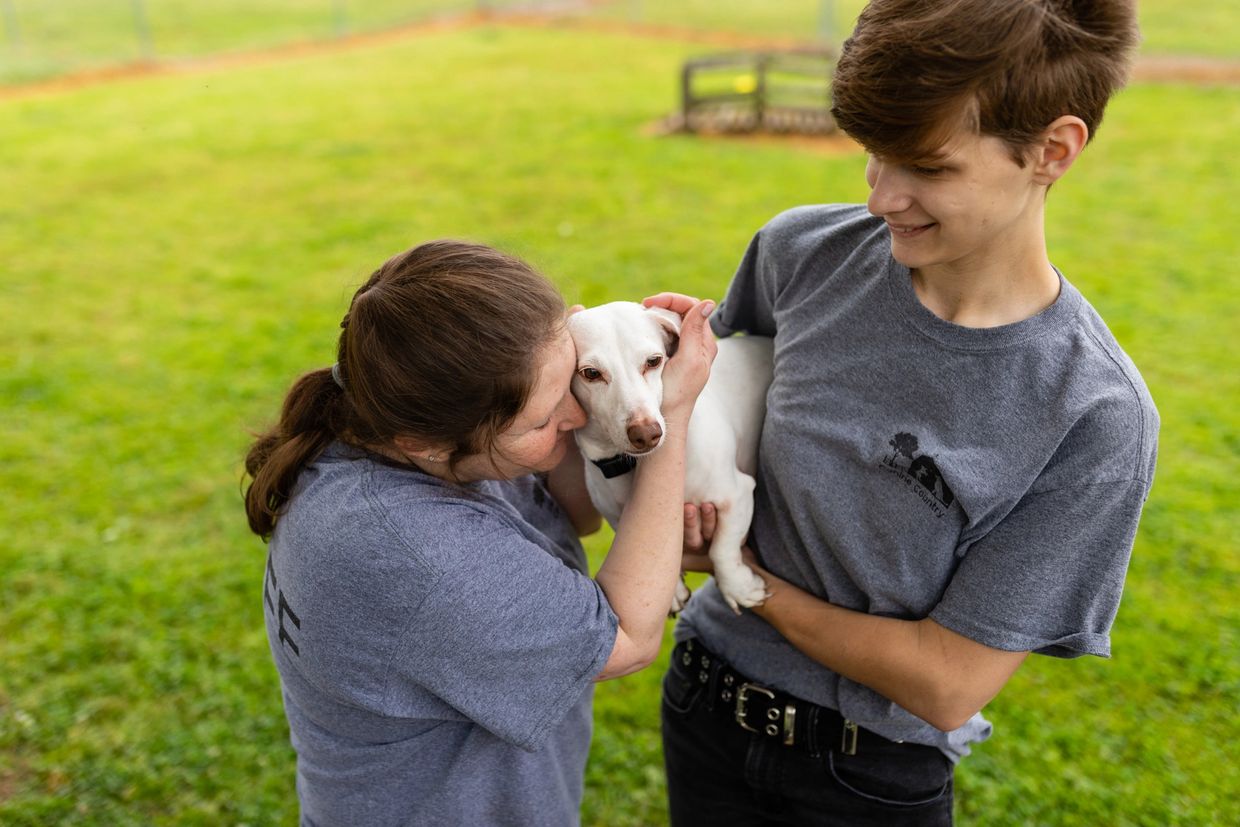 a woman and a boy with a cute white dog