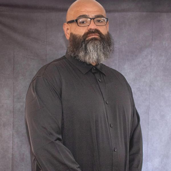 Man with glasses and a full beard wearing a black shirt.
