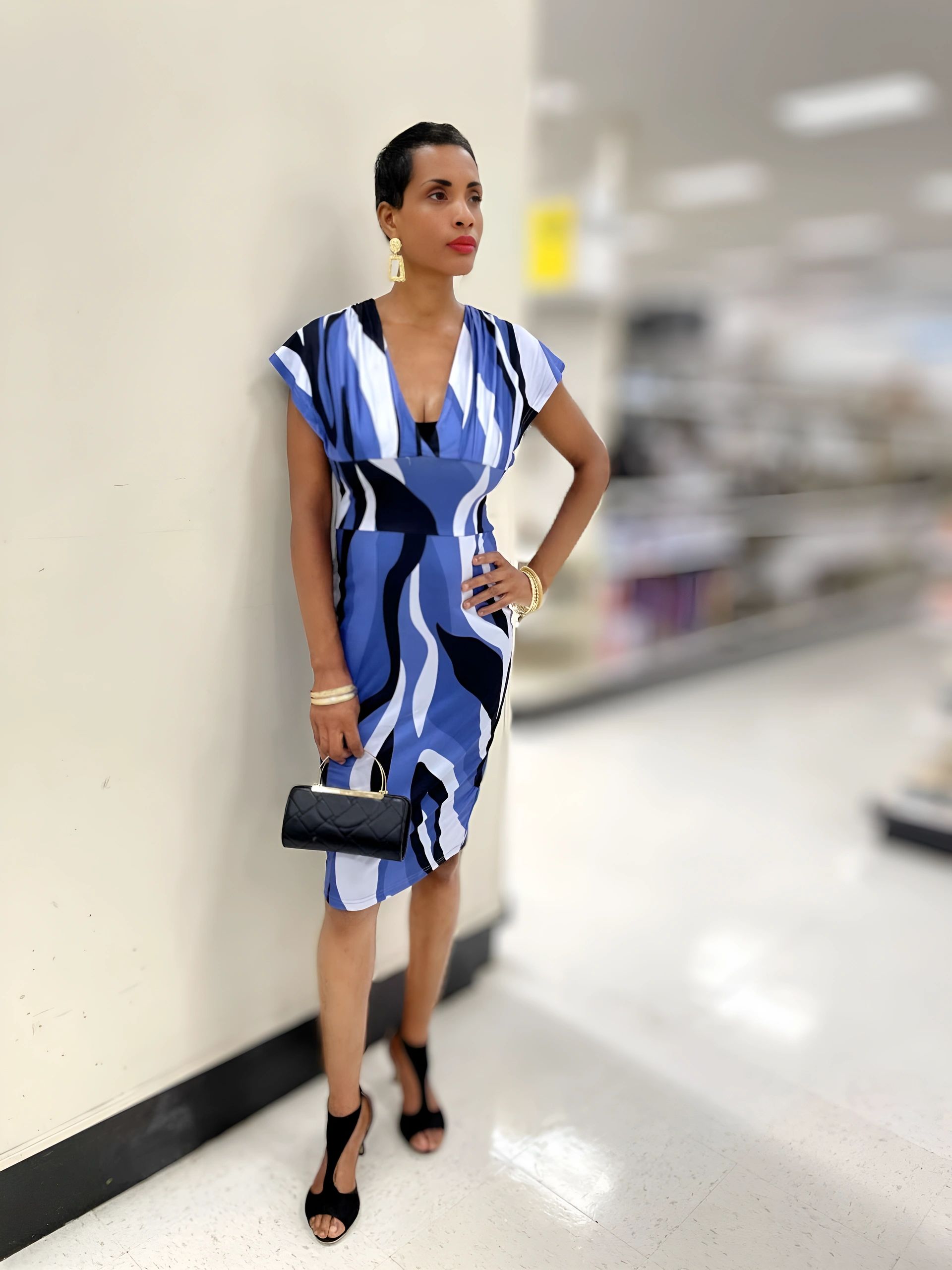 Woman in a stylish blue and white dress posing indoors with accessories.