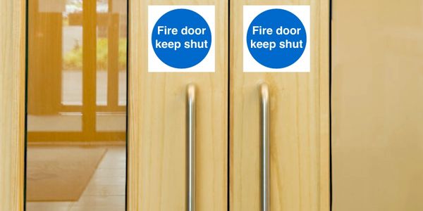 Double wooden fire doors with 'Fire door keep shut' signs and metal handles.