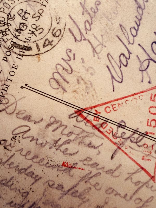 Close-up of an old handwritten postcard with stamps and censorship mark.