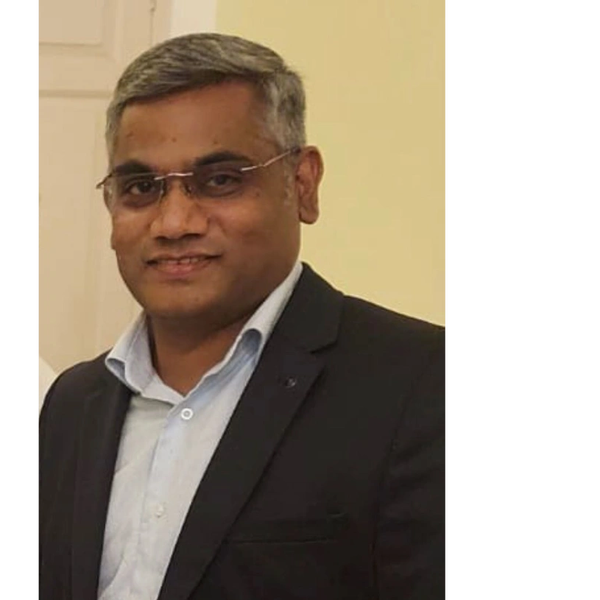 Man wearing glasses and a dark suit smiling at the camera.
