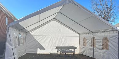 Empty white event tent with a single table inside on a sunny day.