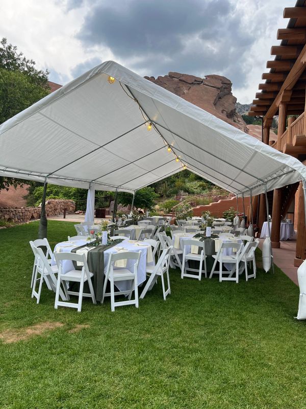 Outdoor event setup with white tents and tables on green lawn.