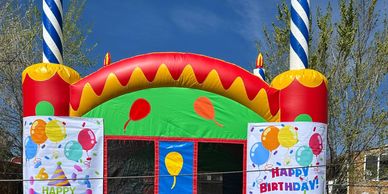 Colorful inflatable bounce house decorated for a birthday party outdoors.