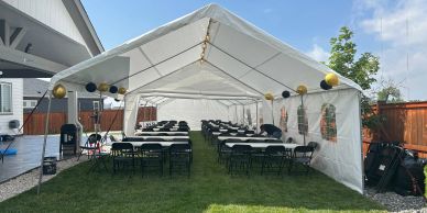 A large white tent with tables and chairs set up for an outdoor event.